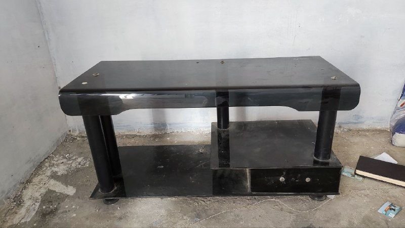 A spacious shade glass TV table with a model is for sale at the price of 550 Afghanis due to immigration